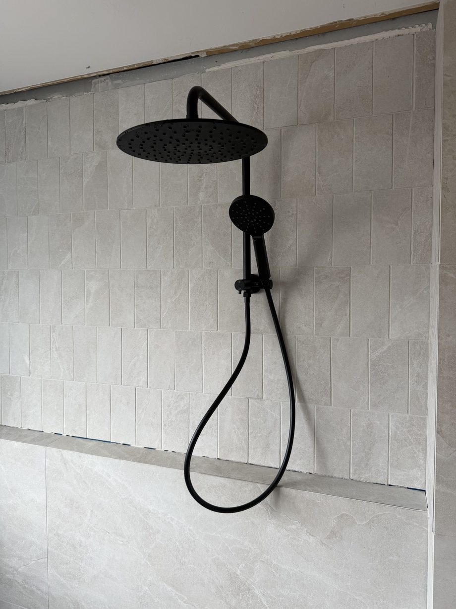 Rain shower against a freshly tiled bathroom wall